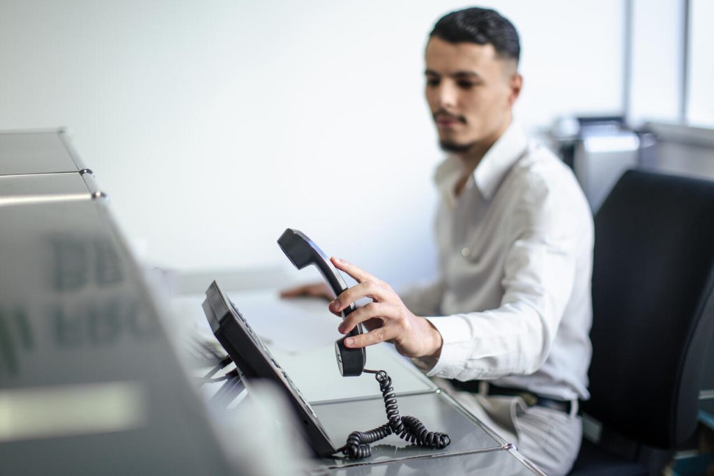 Um recepcionista atendendo uma ligação no telefone