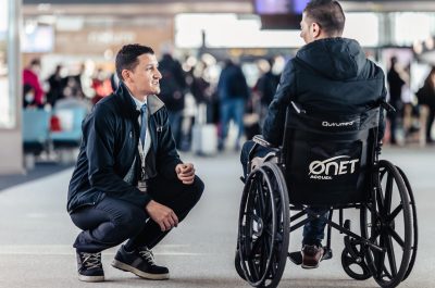 APMR agent accompanying a person with reduced mobility through an airport.